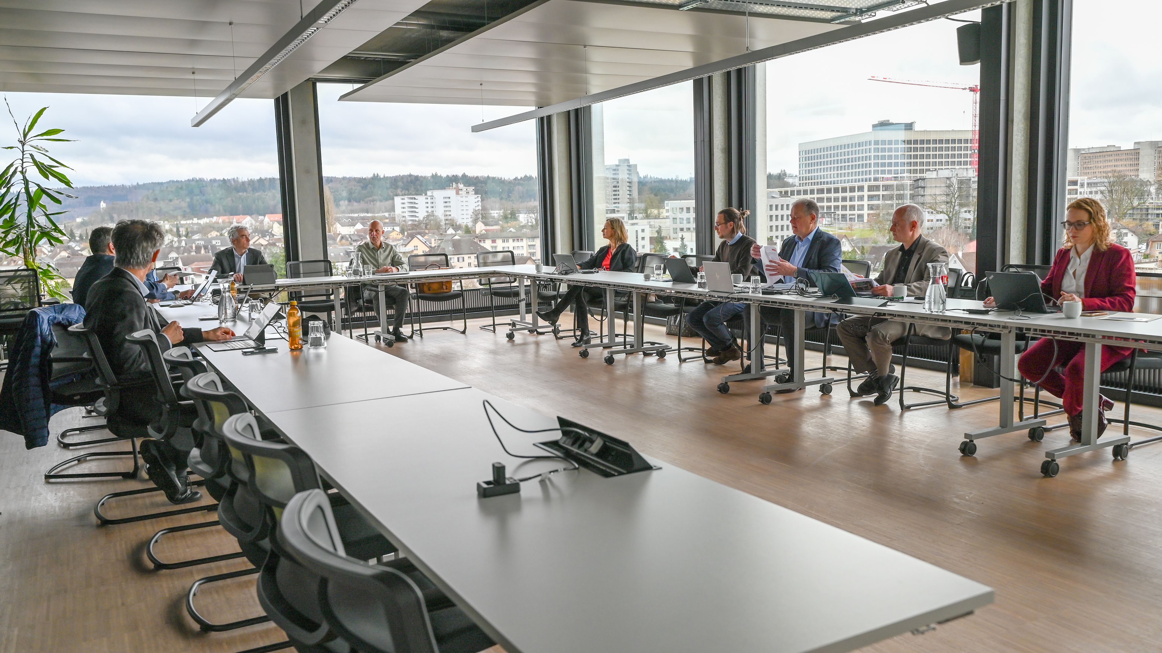 Blick in einen Sitzungsraum bei Eniwa in Aarau: Frauen und Männer nehmen an einer Verwaltungsratssitzung der Swisspower AG teil, im Hintergrund ist die Dächerlandschaft der Stadt Aarau zu sehen.